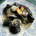 Hand-made black squid ink pierogi with salmon